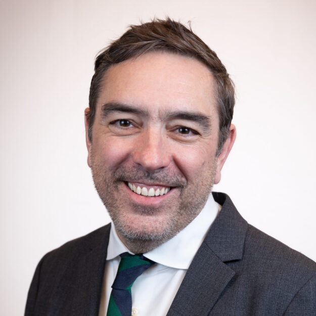 Man in dark grey suit and green and black-striped tie