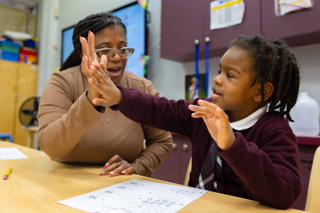 Female teacher and preschool male scholar sharing a hi-five.