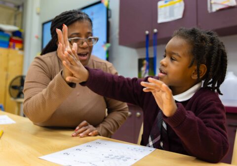 Female teacher and preschool male scholar sharing a hi-five.