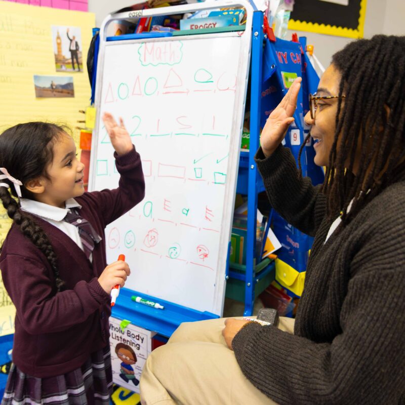 Teacher and pre-school scholar sharing a hi-five