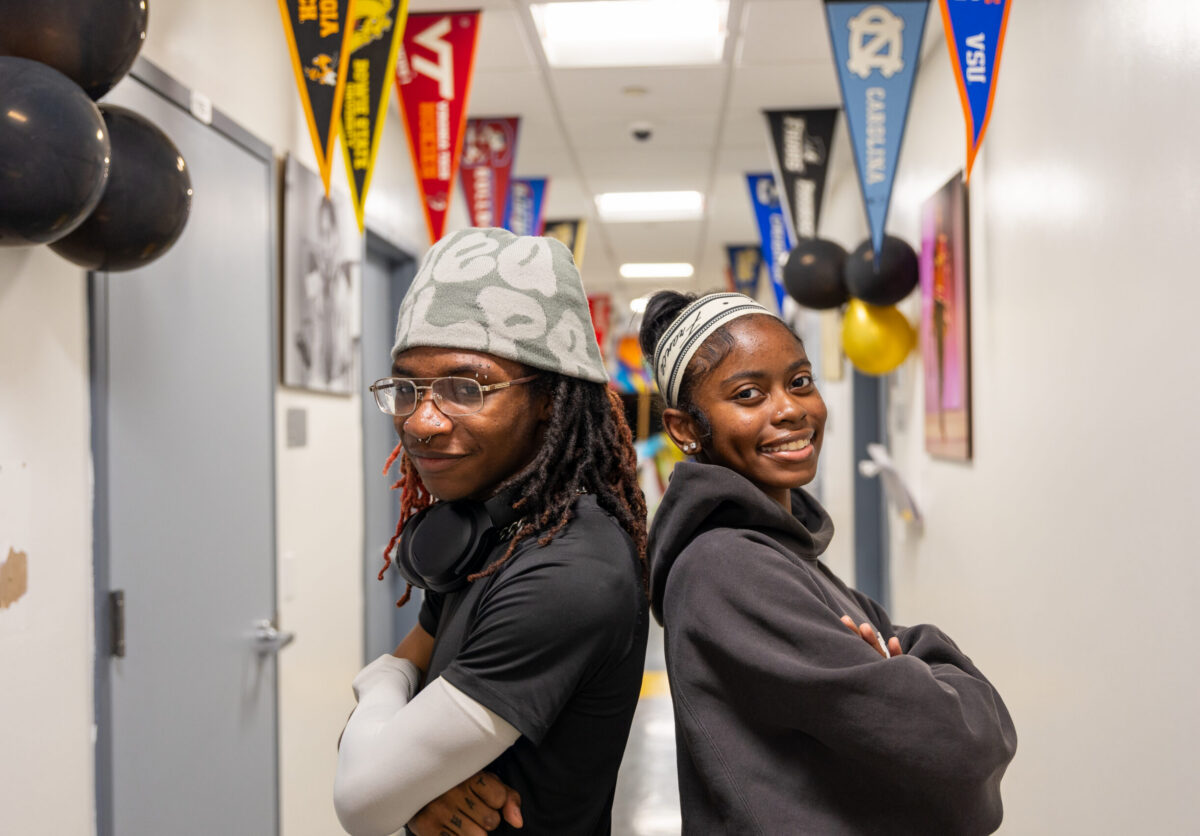 Scholars smiling and standing back to back in the hallway