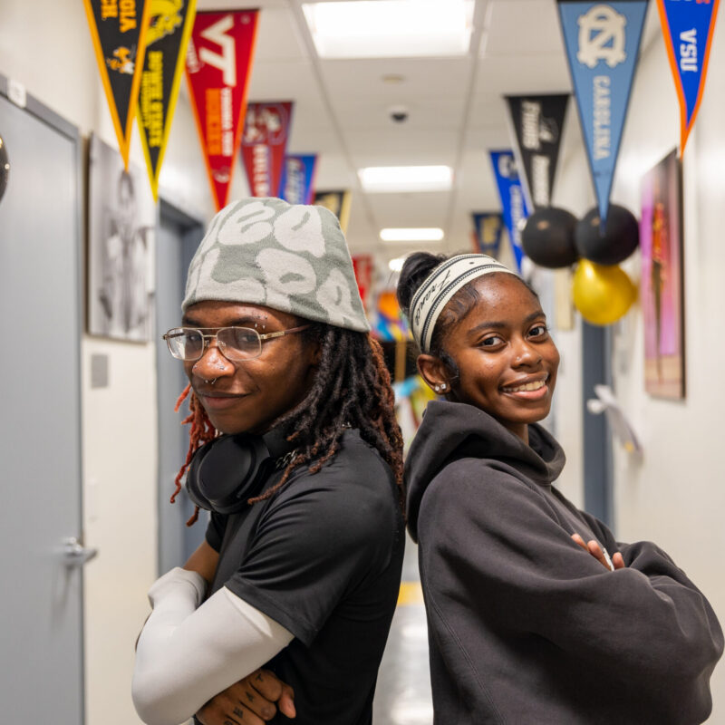 Scholars smiling and standing back to back in the hallway