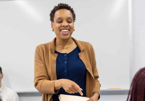 Female professional standing in a classroom speaking to a scholar.
